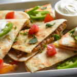 Spicy pork quesadillas on a sheet pan with tomatoes