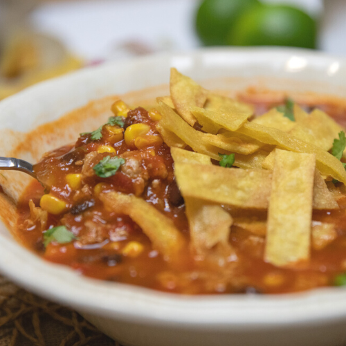 Bowl of ground pork chili with tortilla strips