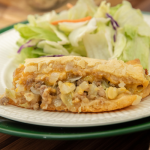 A slice of bierock casserole on a plate with salad behind it.