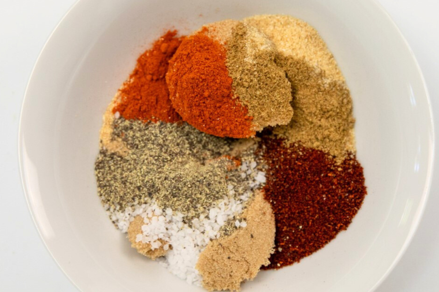 Dry spice ingredients measured in white bowl.