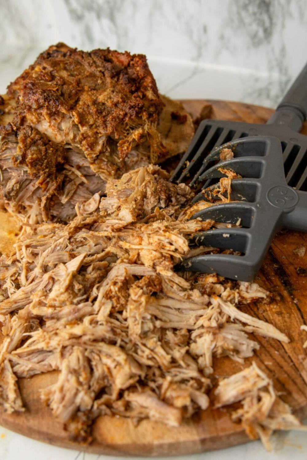 Shredded pulled pork on wooden cutting board.