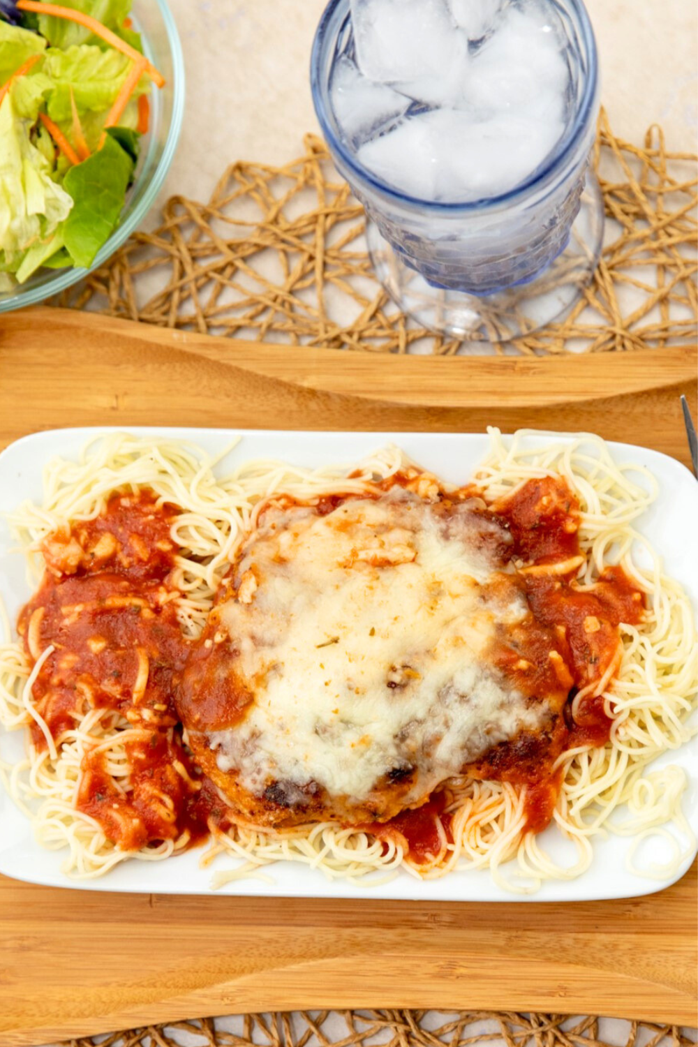 Pork cubed steak parmesan nestled on top of spaghetti noodles and covered by melted cheese.