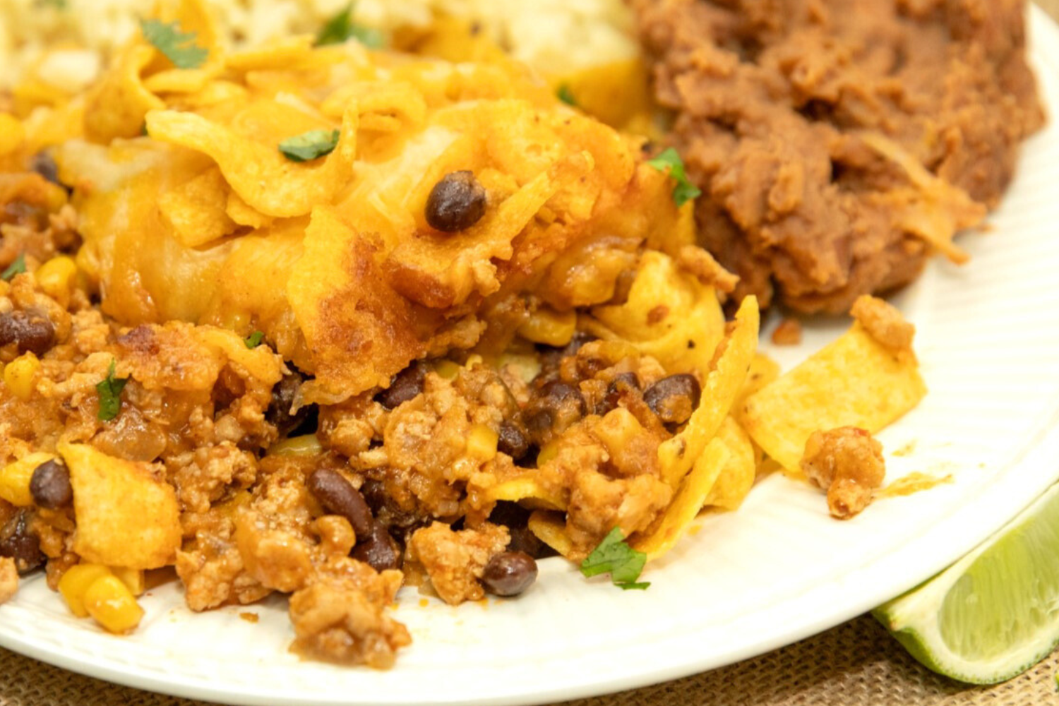 Plate of crunchy corn chips and melty cheese on top of seasoned ground pork.