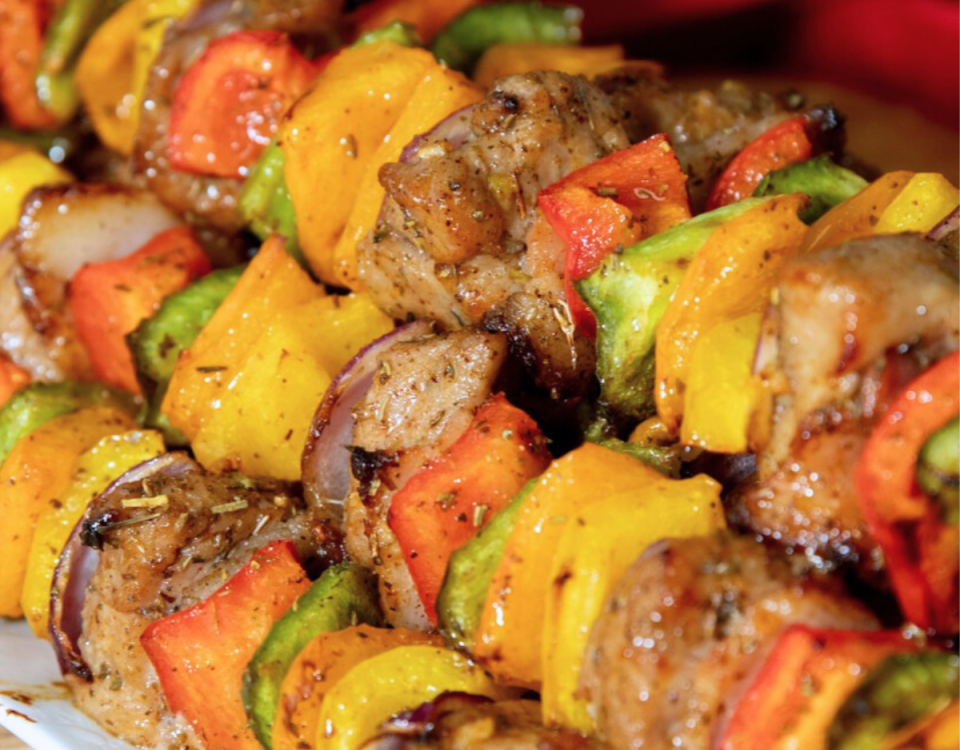 Pork tenderloin, bacon, peppers and onion on a skewer.