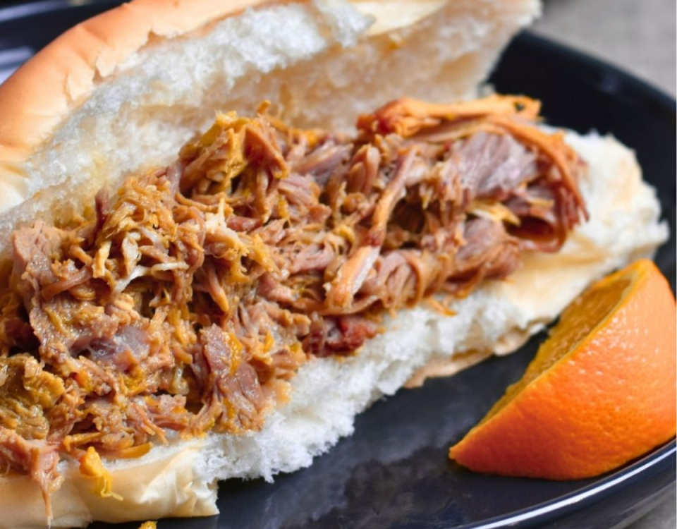 Plated pulled pork on white hoagie bun bread.